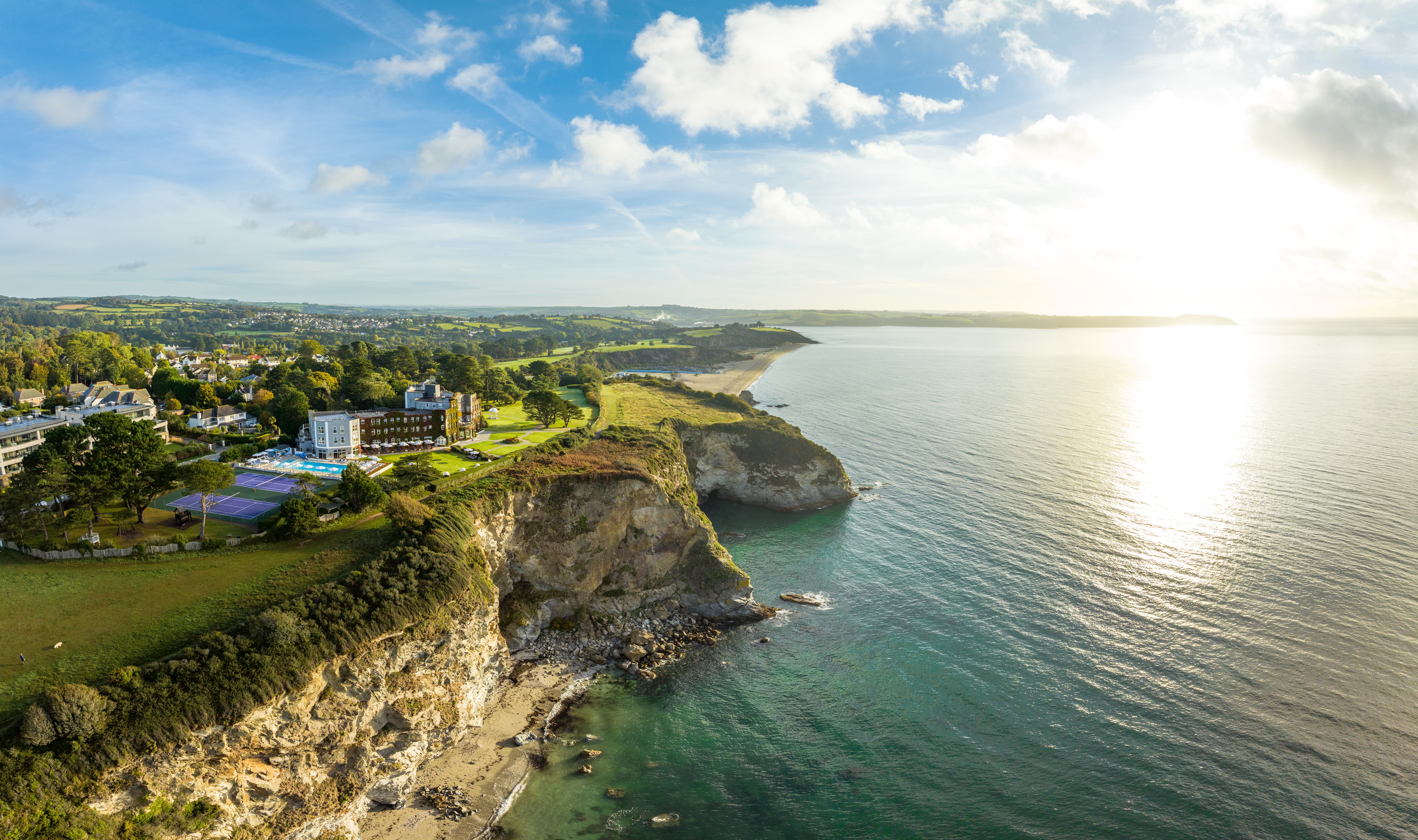 Aerial view of the Carlyon Hotel on the edge of a cliff overlooking the sea
